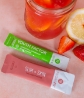 Neora’s Slim & Glow Set featuring Youth Factor Superfood & Antioxidant Boost Powder and NeoraFit Slim + Skin Collagen Powder next to a drink and fruit